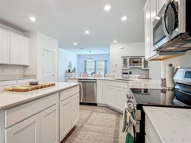 19424 SW 77th Loop, Dunnellon, FL 34432 - kitchen featuring stainless steel appliances, a peninsula, recessed lighting, white cabinetry, and light stone countertops