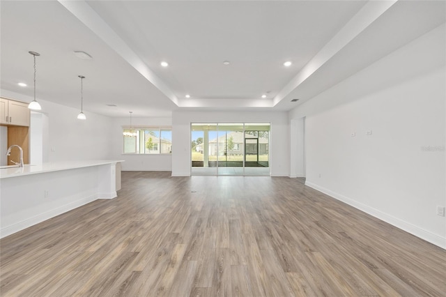 10561 SW 98th Pl, Ocala, FL 34481 - unfurnished living room with recessed lighting, light wood-style flooring, a tray ceiling, and a chandelier