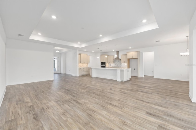 10561 SW 98th Pl, Ocala, FL 34481 - unfurnished living room with a raised ceiling, recessed lighting, light wood-style floors, and a chandelier