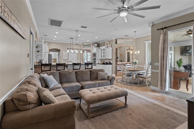 4731 SE 34th St, Ocala, FL 34480 - living room featuring ceiling fan, arched walkways, crown molding, recessed lighting, and a chandelier