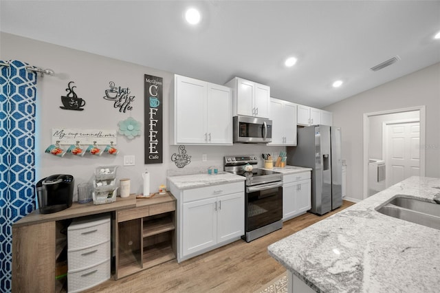 11330 SW 61st Cir, Ocala, FL 34476 - kitchen featuring stainless steel appliances, washer and dryer, light wood-style flooring, white cabinetry, and light stone countertops