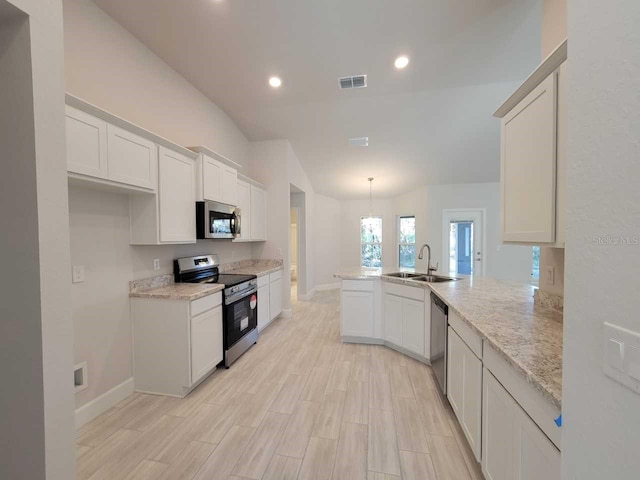 12384 SW 96th Ln, Dunnellon, FL 34432 - kitchen with appliances with stainless steel finishes, a peninsula, light stone countertops, white cabinets, and vaulted ceiling