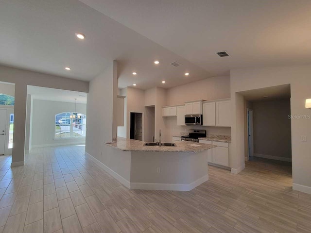 12384 SW 96th Ln, Dunnellon, FL 34432 - kitchen with appliances with stainless steel finishes, white cabinets, light wood-style flooring, light stone counters, and recessed lighting