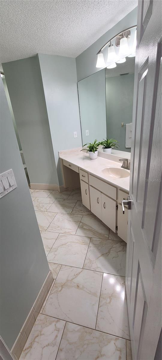 8771 SW 115th St, Ocala, FL 34481 - bathroom featuring marble finish floors, vanity, and a textured ceiling