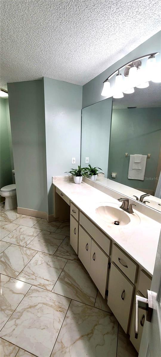 8771 SW 115th St, Ocala, FL 34481 - bathroom with vanity, marble finish floors, and a textured ceiling