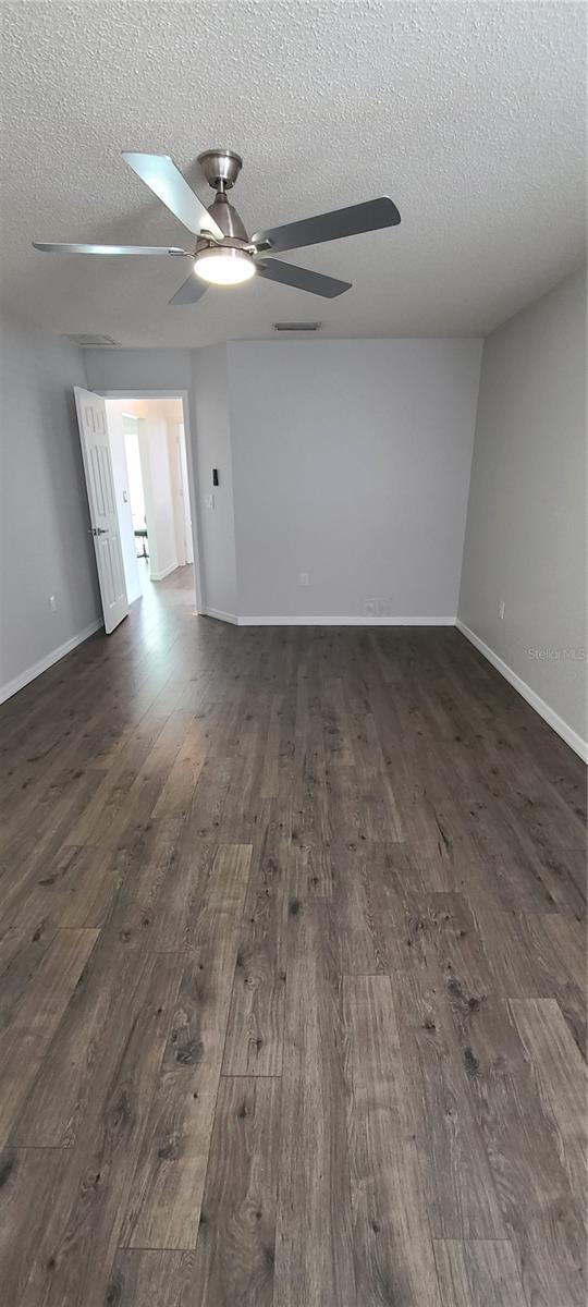 8771 SW 115th St, Ocala, FL 34481 - spare room with a textured ceiling, ceiling fan, and dark wood-style floors