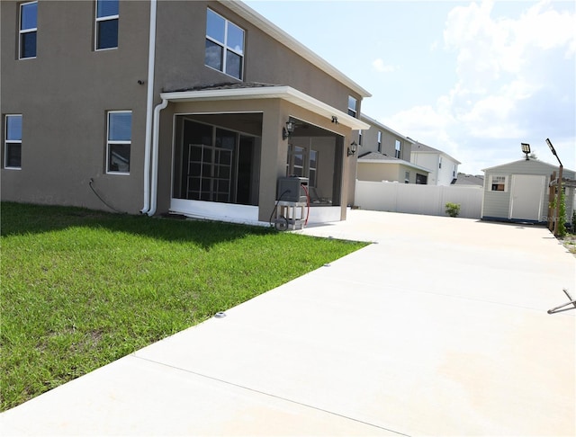 5962 SW 80th Ln, Ocala, FL 34476 - rear view of property featuring a sunroom, a storage unit, stucco siding, a patio, and driveway