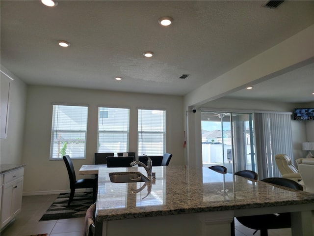 5962 SW 80th Ln, Ocala, FL 34476 - kitchen featuring open floor plan, white cabinetry, recessed lighting, light stone countertops, and a kitchen island with sink