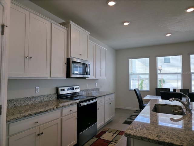 5962 SW 80th Ln, Ocala, FL 34476 - kitchen with stainless steel appliances, white cabinets, recessed lighting, tile patterned flooring, and light stone counters