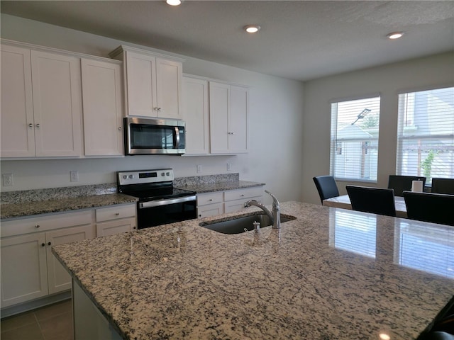 5962 SW 80th Ln, Ocala, FL 34476 - kitchen featuring stainless steel microwave, electric range oven, white cabinetry, recessed lighting, and light stone counters