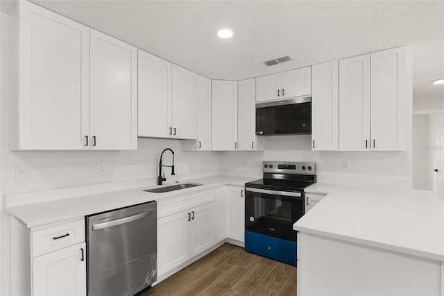 2817 Rheims Ave, Melbourne, FL 32935 - kitchen featuring stainless steel appliances, a peninsula, wood finished floors, light countertops, and white cabinetry