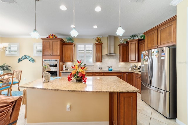 7814 SW 97th Cir, Ocala, FL 34481 - kitchen featuring stainless steel appliances, wall chimney range hood, brown cabinets, a kitchen island, and ornamental molding