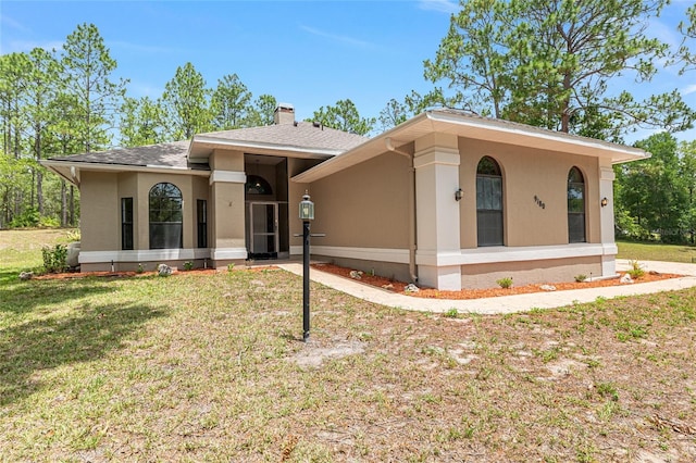 9180 SW 202nd Avenue Rd, Dunnellon, FL 34431 - view of front of property with a front lawn, stucco siding, a chimney, and roof with shingles