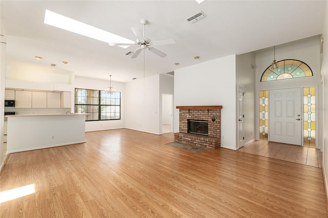 9180 SW 202nd Avenue Rd, Dunnellon, FL 34431 - unfurnished living room with a brick fireplace, light wood-style flooring, ceiling fan, and a chandelier
