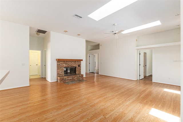 9180 SW 202nd Avenue Rd, Dunnellon, FL 34431 - unfurnished living room featuring a skylight, light wood finished floors, a brick fireplace, and ceiling fan