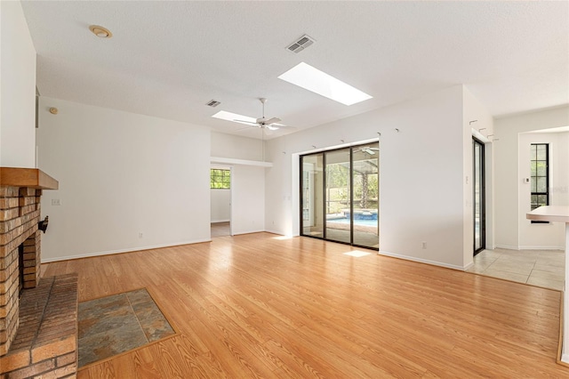 9180 SW 202nd Avenue Rd, Dunnellon, FL 34431 - unfurnished living room featuring a skylight, light wood finished floors, healthy amount of natural light, and a fireplace
