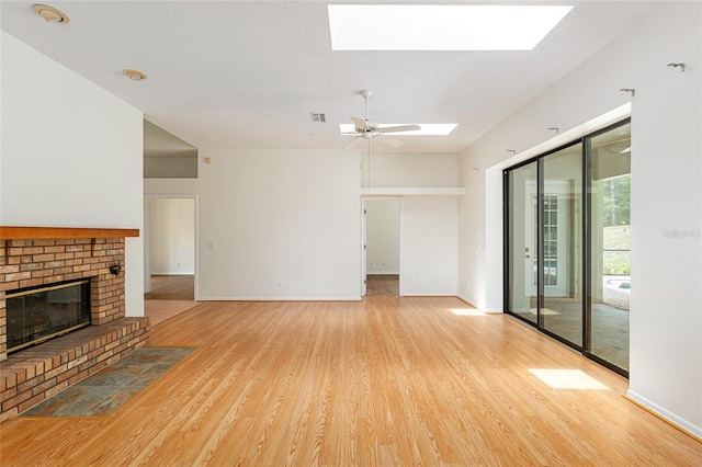 9180 SW 202nd Avenue Rd, Dunnellon, FL 34431 - unfurnished living room featuring a skylight, light wood finished floors, a fireplace, and ceiling fan