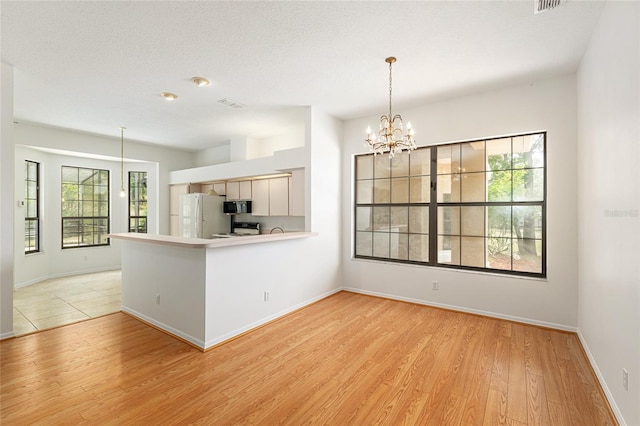 9180 SW 202nd Avenue Rd, Dunnellon, FL 34431 - kitchen with freestanding refrigerator, black microwave, light wood-style flooring, and a chandelier