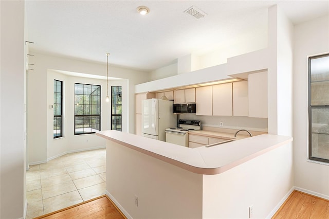 9180 SW 202nd Avenue Rd, Dunnellon, FL 34431 - kitchen featuring white appliances, light countertops, a peninsula, hanging light fixtures, and light wood finished floors