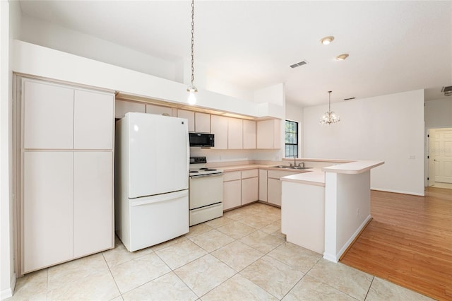 9180 SW 202nd Avenue Rd, Dunnellon, FL 34431 - kitchen featuring white appliances, a peninsula, a chandelier, light countertops, and hanging light fixtures