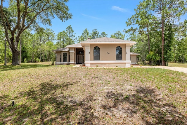 9180 SW 202nd Avenue Rd, Dunnellon, FL 34431 - view of front of home with stucco siding, a front yard, a chimney, and driveway