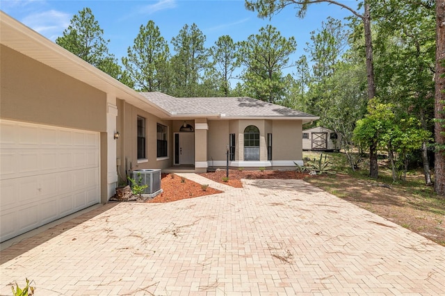 9180 SW 202nd Avenue Rd, Dunnellon, FL 34431 - view of front of property featuring stucco siding, decorative driveway, an attached garage, a storage shed, and a shingled roof
