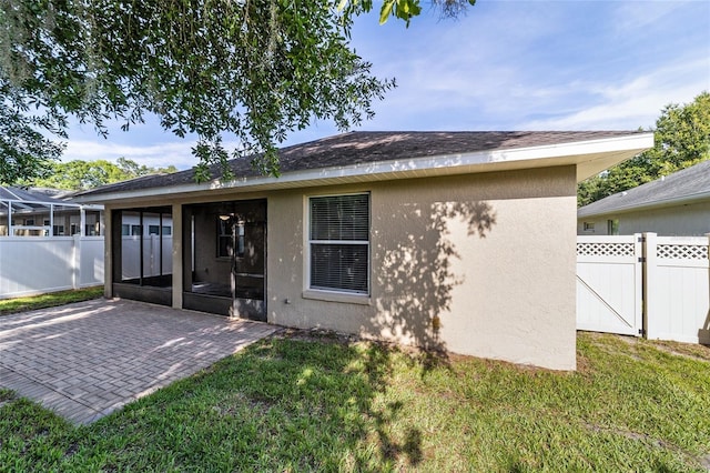 2127 NE 38th Ter, Ocala, FL 34470 - back of house with a sunroom, stucco siding, and a patio