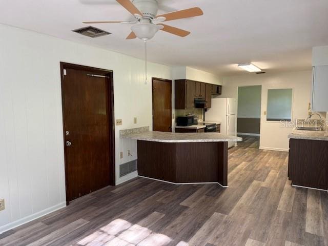 4701 NE 9th St, Ocala, FL 34470 - kitchen with light countertops, dark wood-style flooring, dark brown cabinetry, ceiling fan, and freestanding refrigerator