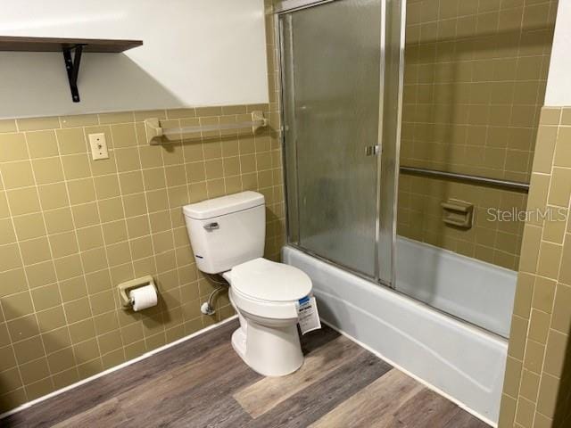 4701 NE 9th St, Ocala, FL 34470 - full bath with tile walls, wood finished floors, bath / shower combo with glass door, and wainscoting