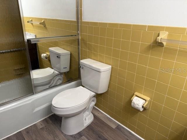 4701 NE 9th St, Ocala, FL 34470 - full bathroom with tile walls, wood finished floors, shower / bath combination with glass door, and wainscoting