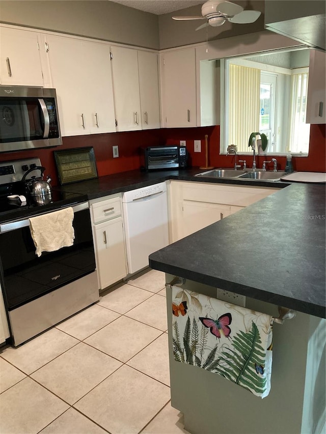 8450 SW 90th St Unit D, Ocala, FL 34481 - kitchen with stainless steel appliances, white cabinets, ceiling fan, light tile patterned flooring, and dark countertops