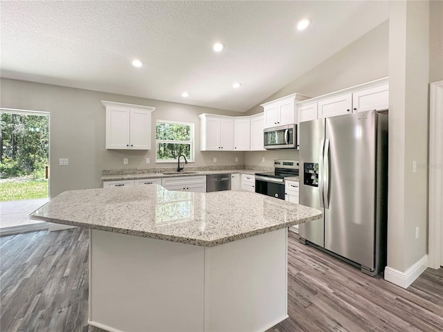 3679 E Bernice St, Inverness, FL 34453 - kitchen featuring stainless steel appliances, wood finished floors, white cabinets, a center island, and light stone countertops