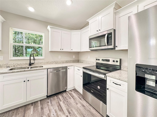 3679 E Bernice St, Inverness, FL 34453 - kitchen featuring appliances with stainless steel finishes, light wood finished floors, white cabinetry, recessed lighting, and light stone countertops