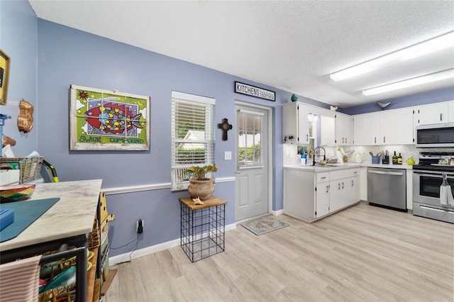 8841 SW 91st St Unit A, Ocala, FL 34481 - kitchen with appliances with stainless steel finishes, light countertops, light wood-type flooring, white cabinets, and a textured ceiling