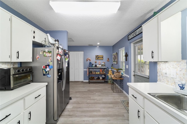 8841 SW 91st St Unit A, Ocala, FL 34481 - kitchen with light wood-style floors, light countertops, decorative backsplash, a textured ceiling, and white cabinetry