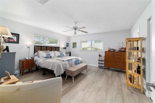 8841 SW 91st St Unit A, Ocala, FL 34481 - bedroom with light wood finished floors, multiple windows, a textured ceiling, and a ceiling fan