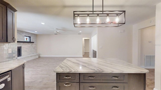 4121 SW 6th Ave, Ocala, FL 34471 - kitchen with dark brown cabinetry, a ceiling fan, light wood-style floors, a fireplace, and light stone counters
