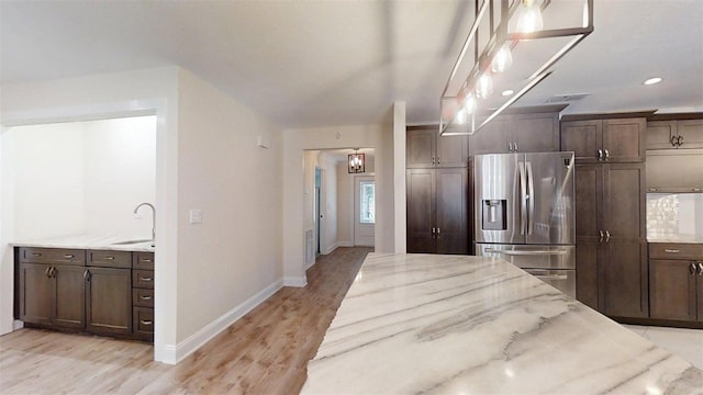 4121 SW 6th Ave, Ocala, FL 34471 - kitchen with stainless steel fridge, light stone countertops, light wood finished floors, dark brown cabinetry, and recessed lighting