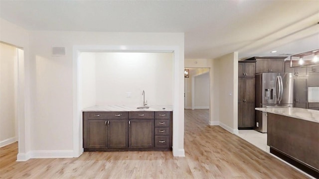 4121 SW 6th Ave, Ocala, FL 34471 - kitchen with stainless steel fridge, light wood-style floors, dark brown cabinetry, and light stone counters