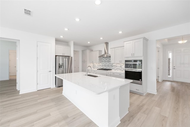 10032 SW 85th Place Rd, Ocala, FL 34481 - kitchen featuring stainless steel appliances, wall chimney exhaust hood, an island with sink, light wood-style flooring, and recessed lighting