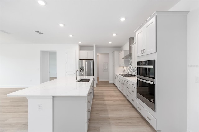 10032 SW 85th Place Rd, Ocala, FL 34481 - kitchen with appliances with stainless steel finishes, recessed lighting, an island with sink, wall chimney range hood, and white cabinetry