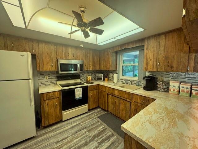 916 Jones Ave, Inverness, FL 34453 - kitchen with white appliances, brown cabinetry, backsplash, light countertops, and ceiling fan