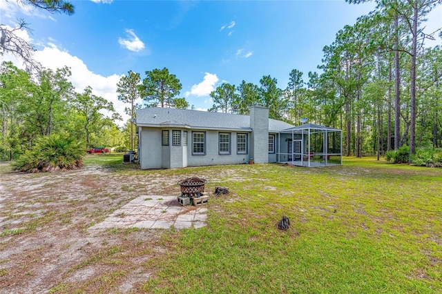 12320 SW 62nd Pl, Ocala, FL 34481 - back of property featuring a fire pit, a chimney, a yard, stucco siding, and a lanai