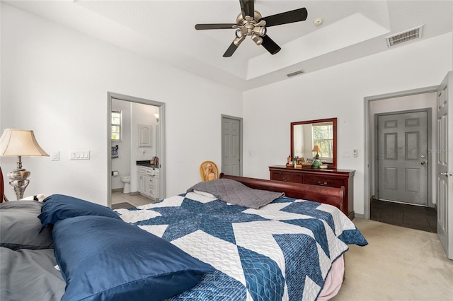 12320 SW 62nd Pl, Ocala, FL 34481 - bedroom with light tile patterned flooring, a tray ceiling, ensuite bathroom, a ceiling fan, and light carpet