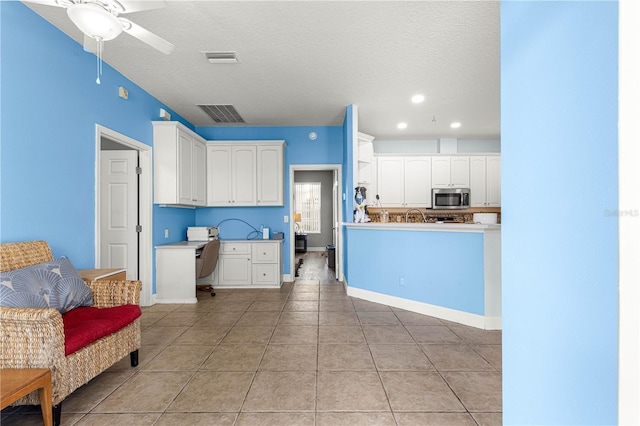 6551 SE 11th Loop, Ocala, FL 34472 - kitchen with stainless steel microwave, white cabinetry, light tile patterned floors, a textured ceiling, and a ceiling fan
