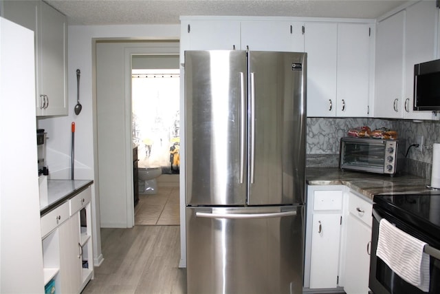 8650 SW 108th Pl, Ocala, FL 34481 - kitchen with stainless steel appliances, light wood-style flooring, white cabinets, and decorative backsplash