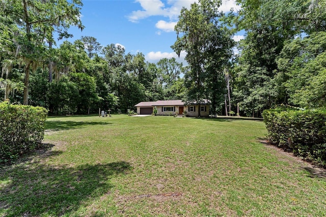 19130 NW 60th Ave, Reddick, FL 32686 - view of green lawn featuring an attached garage and a wooded view