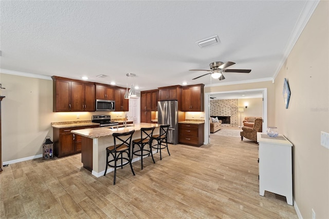 19130 NW 60th Ave, Reddick, FL 32686 - kitchen featuring stainless steel appliances, a fireplace, a kitchen breakfast bar, ceiling fan, and light wood-type flooring
