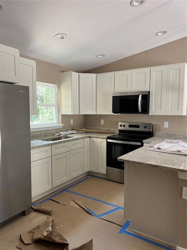 19622 SW Marine Blvd, Dunnellon, FL 34431 - kitchen featuring appliances with stainless steel finishes, a textured ceiling, vaulted ceiling, white cabinetry, and light stone counters