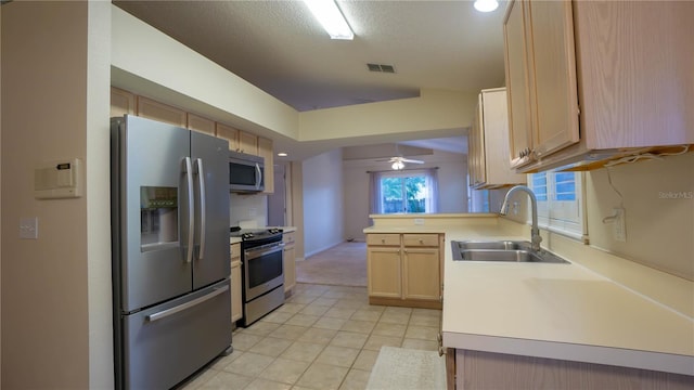 949 Woodsong Way, Clermont, FL 34714 - kitchen featuring stainless steel appliances, light brown cabinetry, light countertops, a ceiling fan, and a peninsula